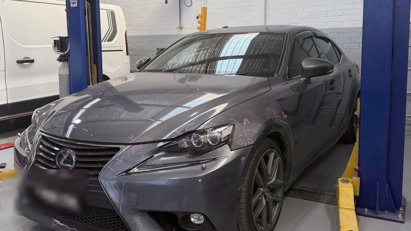 A sedan up on the hoist inside the Fineline workshop, in for inspection