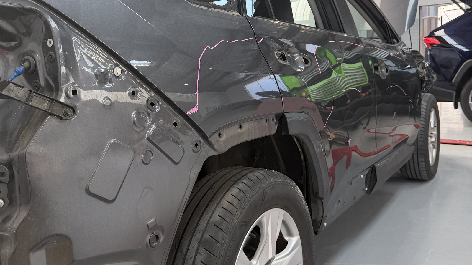 A rear quarter panel in primer on a car in the Fineline workshop, part way through repair