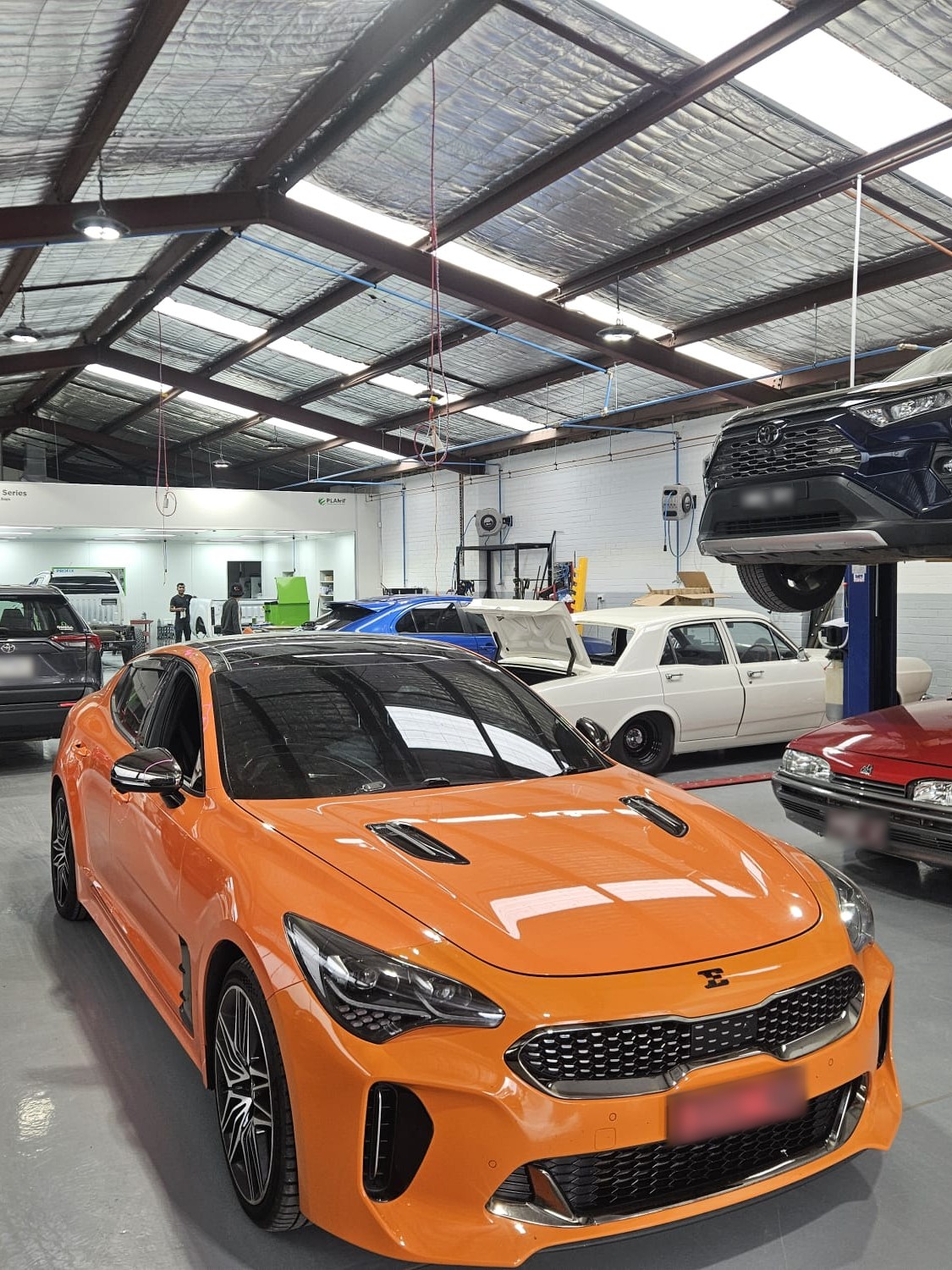 Cars on the Fineline workshop floor in Reservoir, with the spray booth behind them